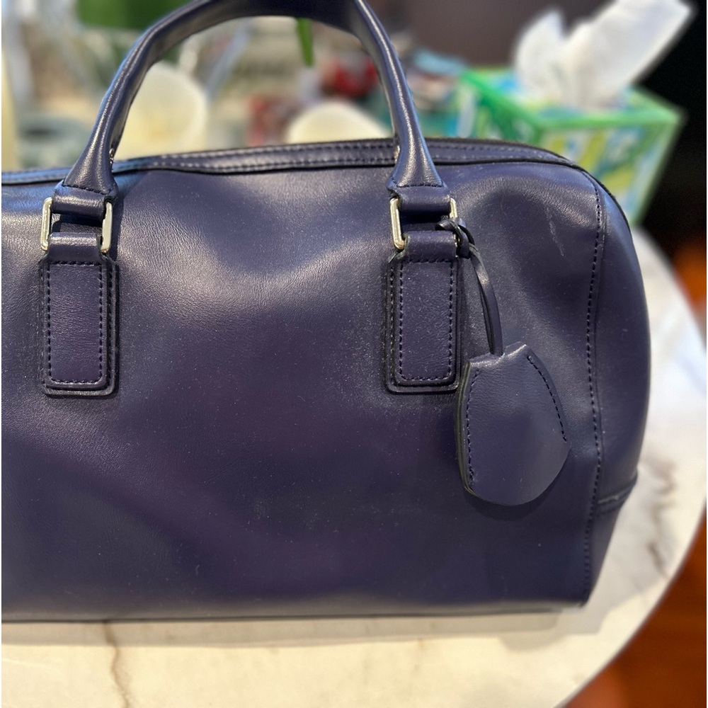 It’s a BCBG Maxazria bag with a lock.The color is bluish violet.